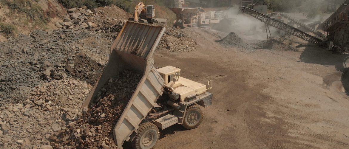 Truck unloads stones in a pile. Landscape of coal mining process. Heaps of stones and dust from sand.