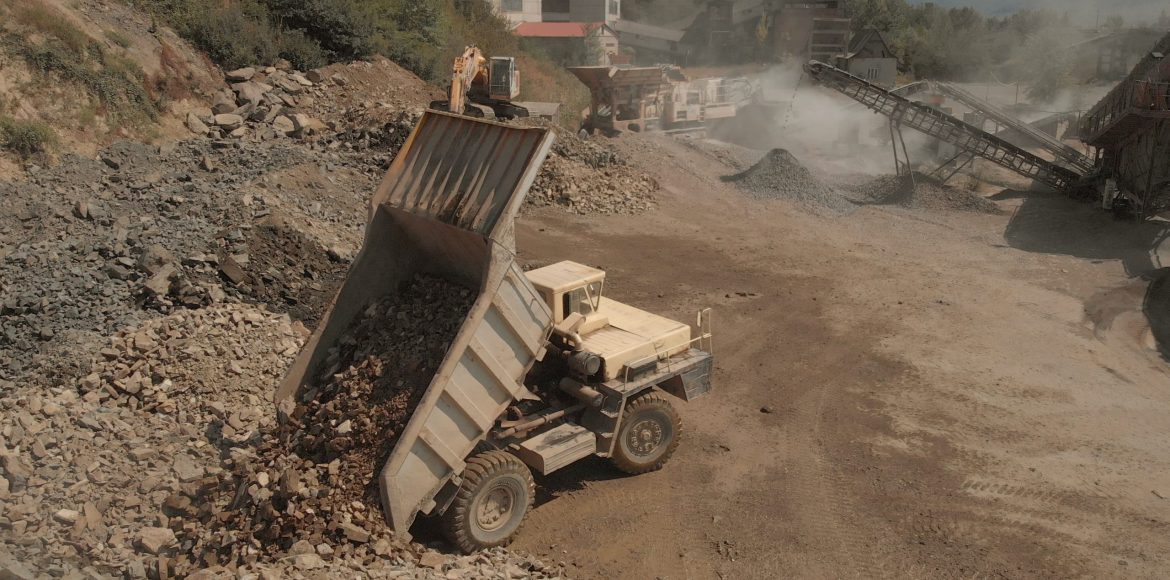 Truck unloads stones in a pile. Landscape of coal mining process. Heaps of stones and dust from sand.