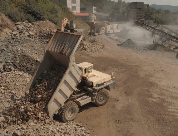 Truck unloads stones in a pile. Landscape of coal mining process. Heaps of stones and dust from sand.